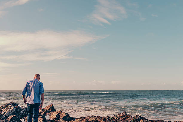 istock Man walking across rocks at the shoreline 612850846