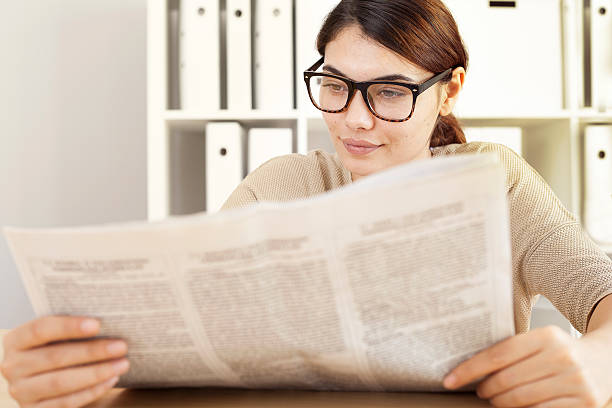 istock Young woman reading newspaper 612851134