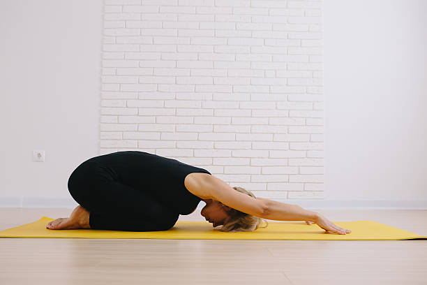 istock woman doing childs pose in yoga class 612851654