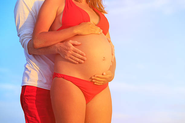istock Happy pregnant couple at beach 612851674