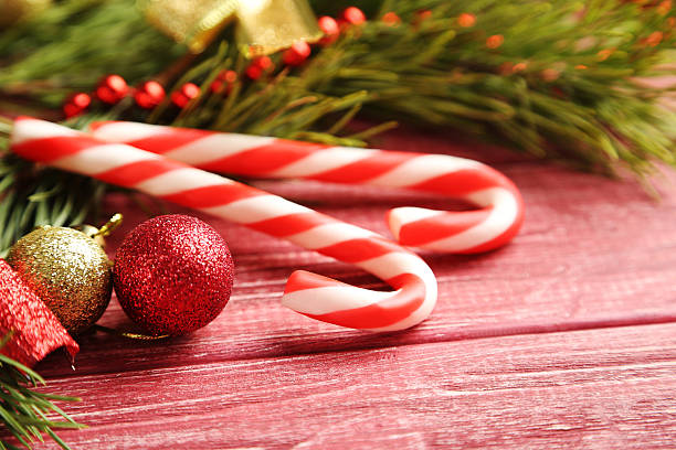 istock Christmax tree branch with baubles, candies on red wooden table 612851842