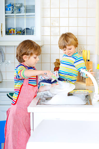 istock Two little kid boys washing dishes in domestic kitchen 612853576