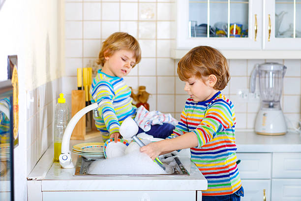 istock Two little kid boys washing dishes in domestic kitchen 612853684