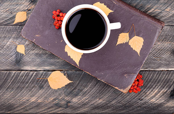 istock Coffee cup, old book, autumn leaves and dried rowan 612855126