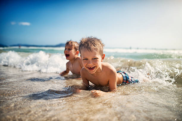 바다에서 해변에 누워 웃고있는 어린 소년 - summer beach vacations sand 뉴스 사진 이미지