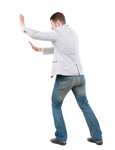 istock back view of business man pushes wall. 612857188