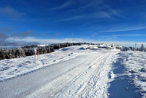 winter hiking trail near Geiereck hill in Fischbacher Alpen mountains in Styria with blue sky and clouds