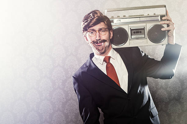 CEO With Boombox Stereo A corporate manager type business man in full suit, big combover hairstyle and mustache looks at the camera with a large vintage portable stereo over his shoulder in hip hop culture style.  Intentional cliche look for humor.  Intended to be an ironic juxtaposition of hip-hop and rap music with the serious business world.  Horizontal with copy space. comb over stock pictures, royalty-free photos & images