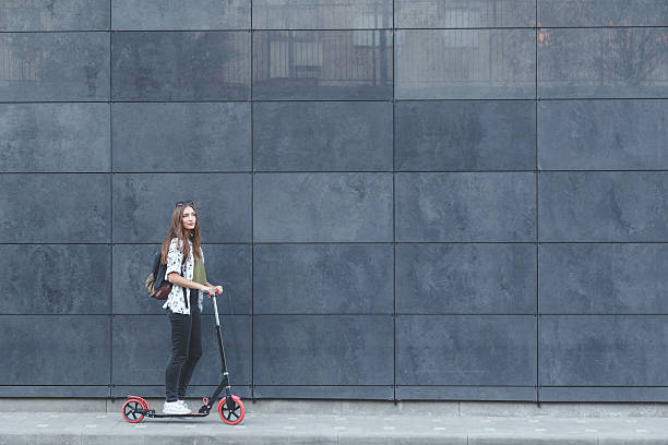 istock Joyful woman riding a kick scooter 613014722