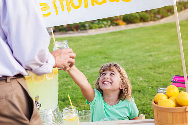 istock Little girl hands lemonade to customer 613017884