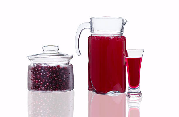 decanter and glass with cranberry juice and a jar with berries stock photo