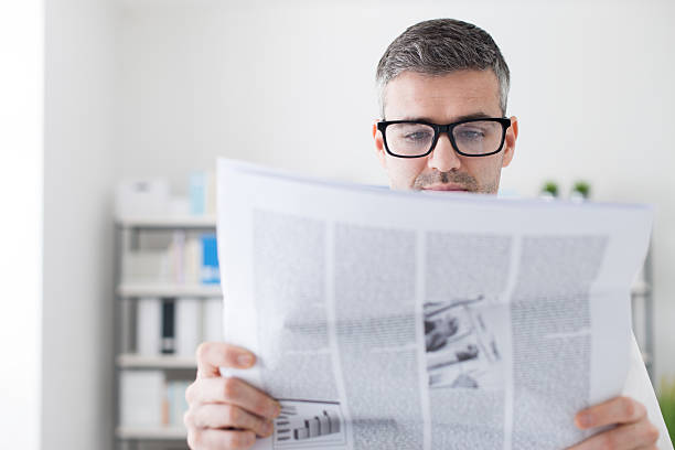 istock Confident businessman reading a newspaper 613020830
