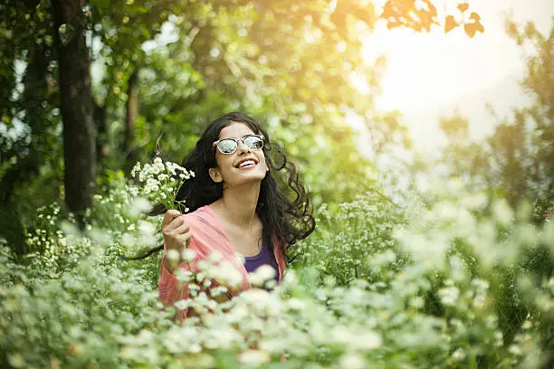 Photo of Portrait of Beautiful Asian girl in meadow holding wild flowers.