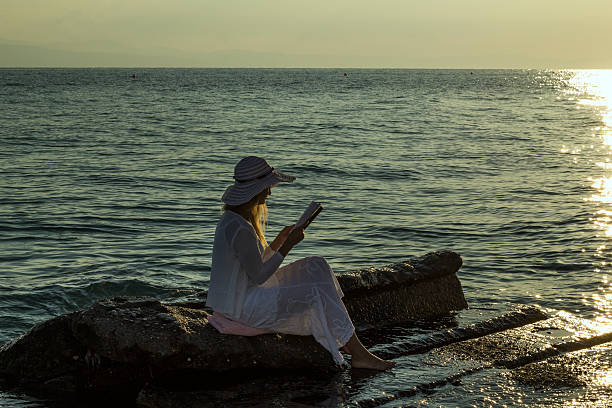 istock Beautiful girl sitting on rock and reading a book. 613024734