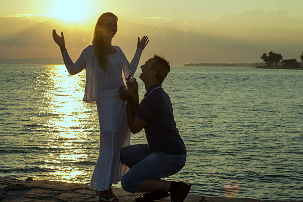 istock Man asking for marry his woman, holding ring at sunrise. 613026086