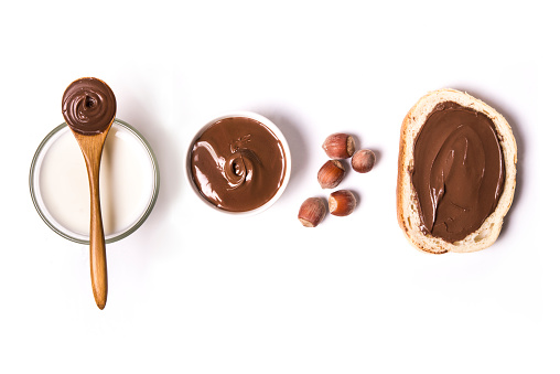 chocolate and hazelnut spread with milk and hazelnuts over white background. top view