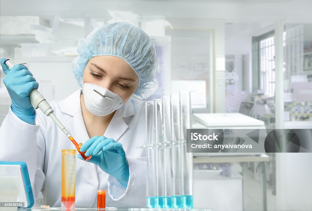 Young energetic female tech or scientist works in laboratory Young female tech or scientist loads liquid sample into test tube with plastic pipette. Shallow DOF, focus on the eyes and hands. Laboratory Stock Photo