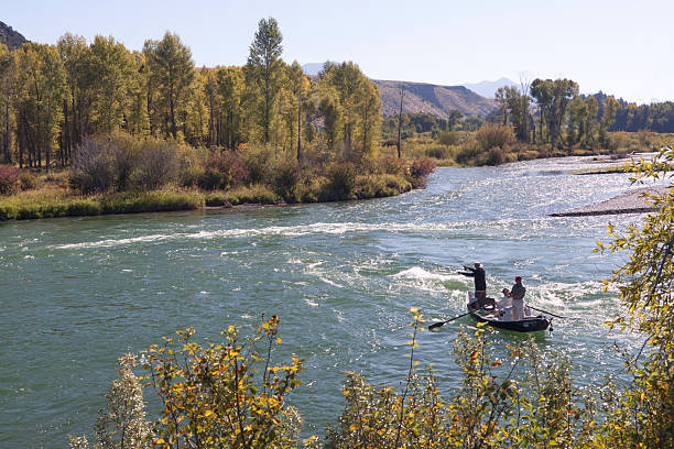Two fly fishermen fish together as one wades in the river while the other fishes from an inflatable raft in Central Oregon.