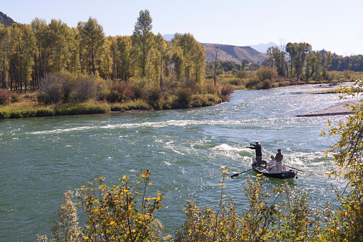 Rigging, Idaho, USA - September 21, 2011: Salmon fishing.  Three man in a small boat on the South Fork Salmon River in Idaho; one man is rowing and two man are fly-fishing. 