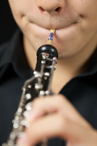 Close up shot of an oboe read in the musicians mouth. This is a shallow depth of field image with focus on the reed.