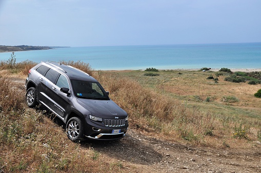 Sciacca, Italy - May 21th, 2013 - Jeep Grand Cherokee (after facelift) stopped on the unmade road. Jeep Grand Cherokee is powered by the 3-liter turbo, direct-injection V6 diesel engine and by three petrol engine options: the 3.6-liter Pentastar V6, the 5.7-liter V8 and the powerful 6.4-liter HEMI V8 engine that powers the high-performance SRT model. The American SUV features a choice of few 4x4 systems. This vehicle is used to get in extremely hard areas, for example on the mountain roads.