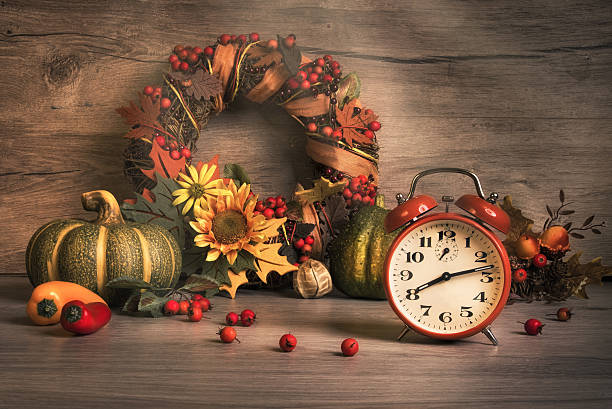 Autumn still life with vintage alarm clock Autumn still life with vintage alarm clock, ornate wreath with berries and ribbons. Design for your Thanksgiving card, seasonal birthday or anniversary greeting. This image is toned. Focus on the clock. thanksgiving holiday hours stock pictures, royalty-free photos & images