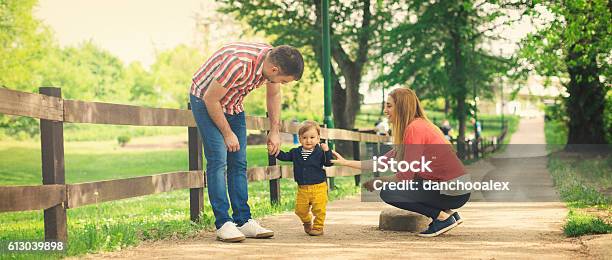Parents And Their Baby Boy Learning To Walk Stock Photo - Download Image Now - Family, Happiness, Public Park