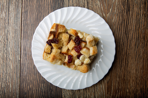 Fresh from the corner bakery, an artisan white chocolate cranberry bread pudding dessert on a rustic background.