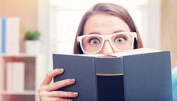 istock Young woman reading a book on her couch 613042356