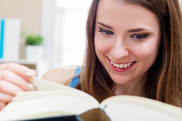 istock Happy young woman reading a book 613042372