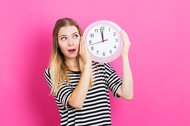 istock Woman holding clock showing nearly 12 613042508
