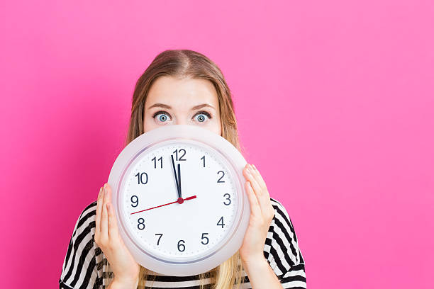 istock Woman holding clock showing nearly 12 613042546