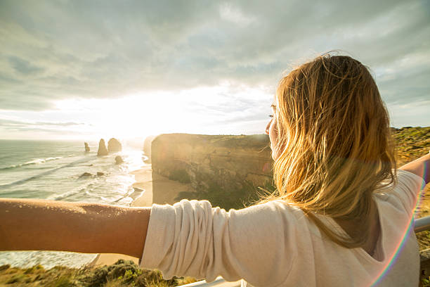 giovane donna braccia distese al tramonto - twelve apostles sea rocks immagine foto e immagini stock