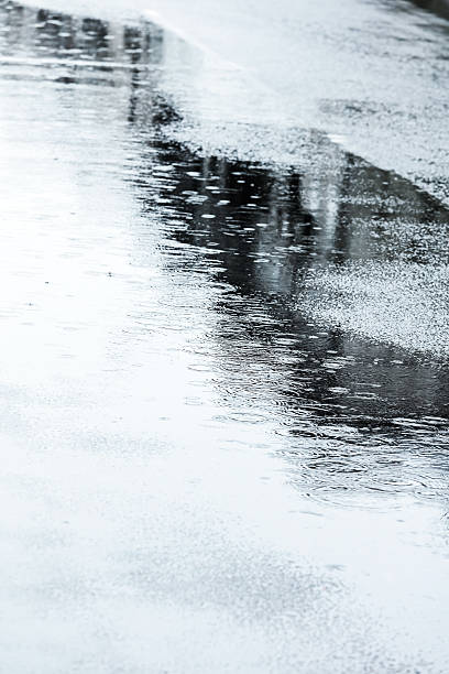 istock wet street sidewalk with raindrops and puddles during rain 613048198