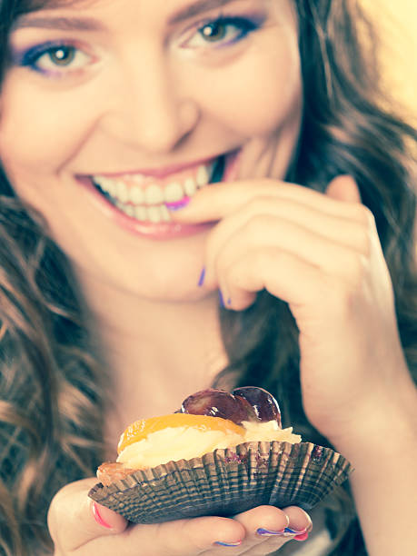 istock Closeup flirty woman eating fruit cake 613053724