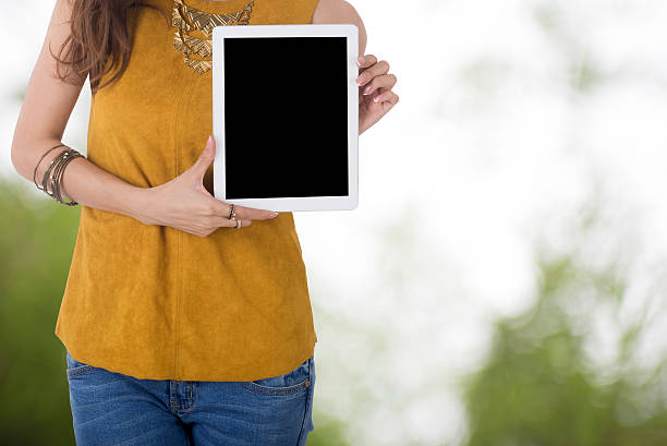 istock business woman hold computer tablet with blur tree background 613054014