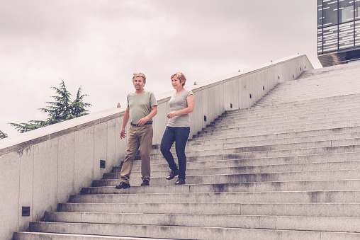 Senior couple looking away in front of business building - outdoors photography. Slovenia, Europe. All logos removed. Nikon D800, full frame, Nikkor 70.0-200.0 mm, aperture 2.8, Copy space.