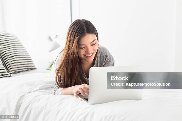 Asian Girl Laying On Bed Playing Laptop Stock Photo - Download Image Now - Laptop, Asian and Indian Ethnicities, Bed - Furniture