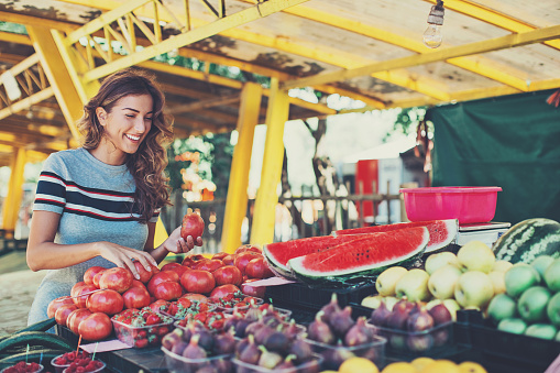 Smiling woman choosing fruits and vegetables on the farmer's market.