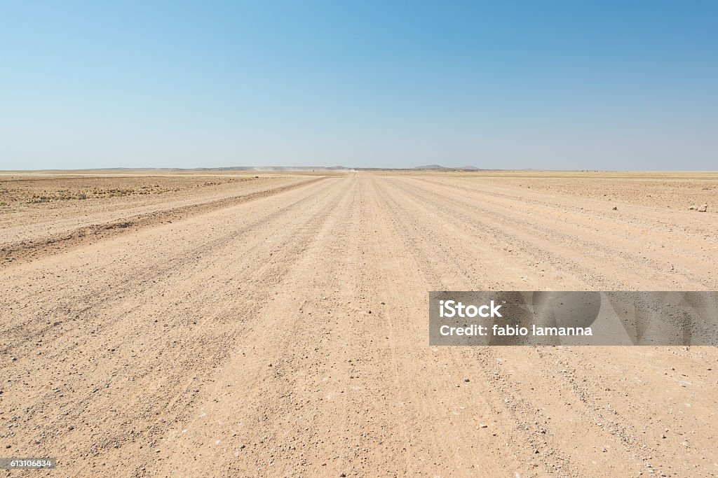 Gravel road crossing the Namib desert, Namibia, Africa Gravel straight road crossing the colorful Namib desert, in the majestic Namib Naukluft National Park, best travel destination in Namibia, Africa. Desert Area Stock Photo