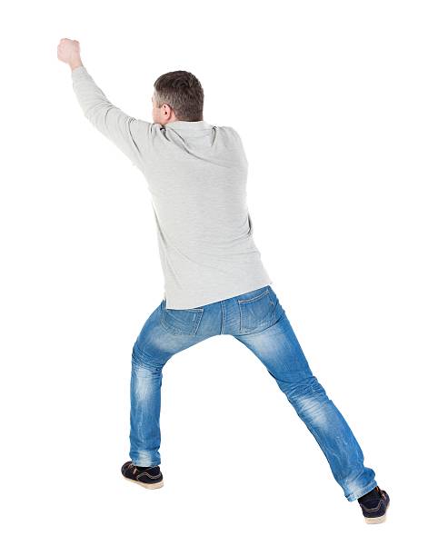 istock back view of standing man pulling a rope from the 613110166