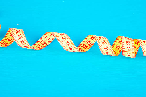 istock yellow measuring tape on a blue background 613110320