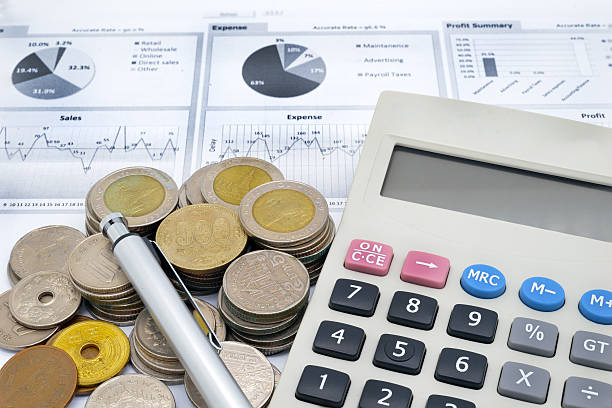 istock calculator, pen and stack of coins on written graph 613112114