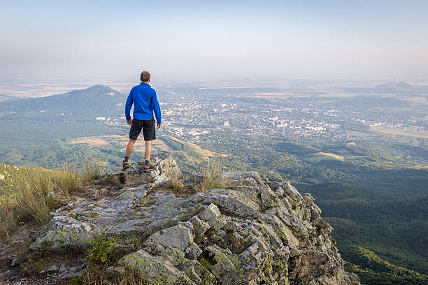 istock Hiker man looking on city from a tall rock 613112528