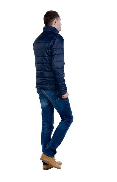 istock Back view of going  handsome man in jeans and jacket. 613113144