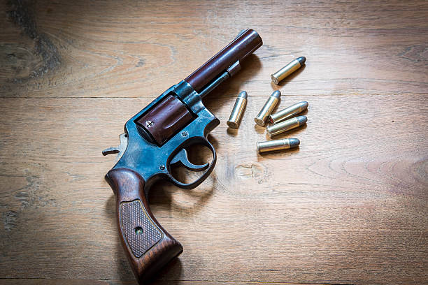 istock Old hand gun and bullets on wooden background 613114472