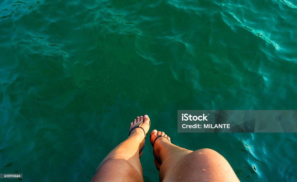 woman leg sitting over the sea relax motion woman leg sitting over the sea on the briged at seaside Adult Stock Photo