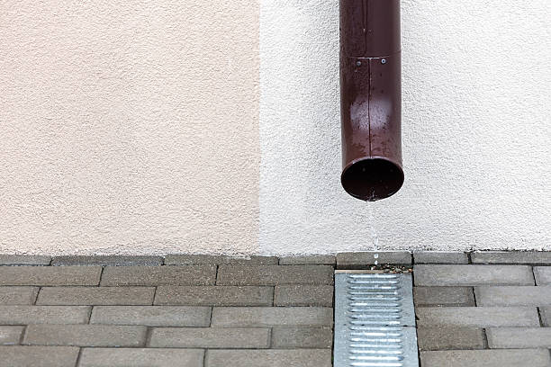 istock rainwater flowing out from metal downspout on pavement 613115094