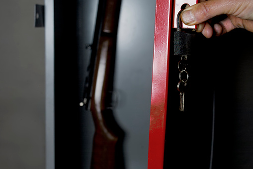 Human hand opening a metal safe with a gun inside, studio cropped shot