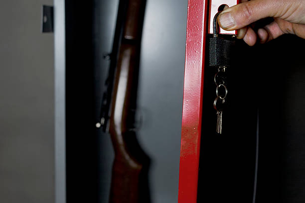 Safe With A Gun Human hand opening a metal safe with a gun inside, studio cropped shot gun stock pictures, royalty-free photos & images